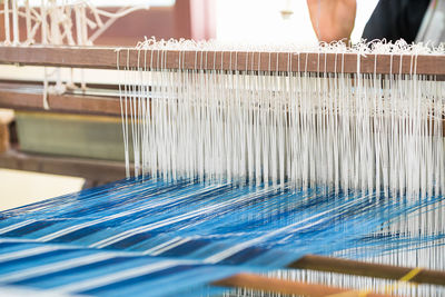 Worker weaving loom in factory