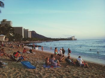 People sitting at beach against sky