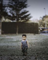 Full length of boy standing on road against trees