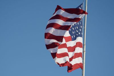 Low angle view of american flag against clear blue sky