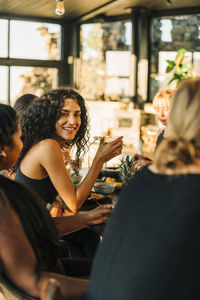 Portrait of smiling young woman sitting with female friends while having breakfast at retreat center