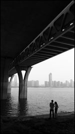 Men standing on bridge over river against sky