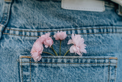 Pink japanese cherry blossoms in the back pocket of women's jeans.