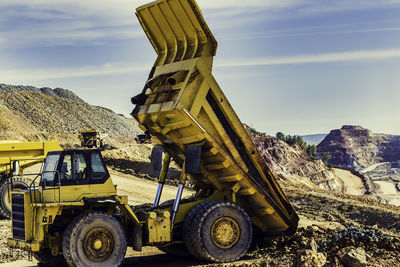 Yellow dumper truck lifted in the mine with other dumper trucks working