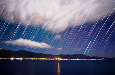 Firework display over mountains against sky at night