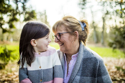 Grandma smiling at granddaughter in outdoor setting.