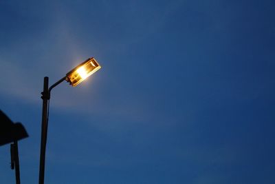 Low angle view of illuminated street light against blue sky