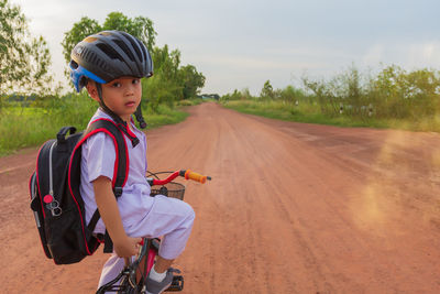 Full length portrait of boy riding bicycle on road against sky