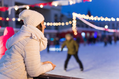 Midsection of woman in illuminated park during winter at night