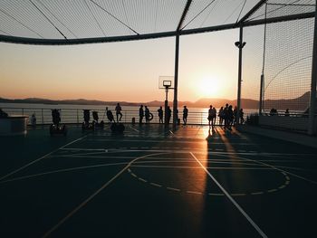 Silhouette people by sea against sky during sunset