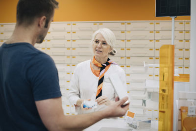 Male customer talking with female owner at medical store