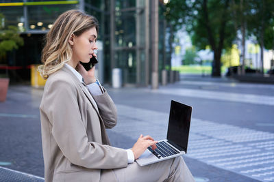 Young woman using laptop while sitting on table