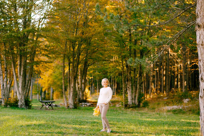 Full length of woman standing amidst trees in forest