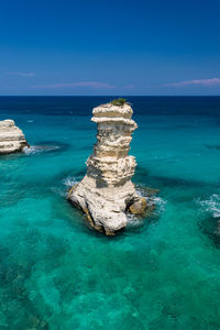 Rocks in sea against blue sky