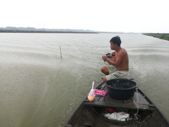 Side view of young man using mobile phone in lake