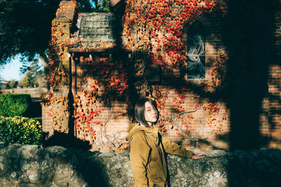 Portrait of young woman standing by tree