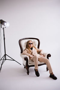 Portrait of young woman sitting on chair against white background