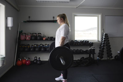 Mid adult woman lifting barbell in gym