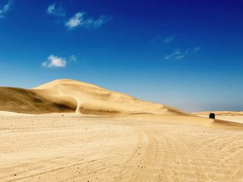 Sand dunes in desert against blue sky