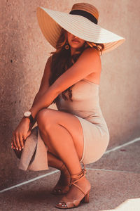 Midsection of woman wearing hat sitting outdoors