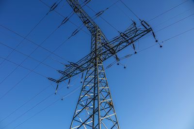 Low angle view of electricity pylon against clear sky