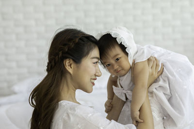 Cheerful mother holding daughter at home