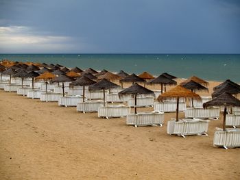 Lounge chairs on beach against clear sky