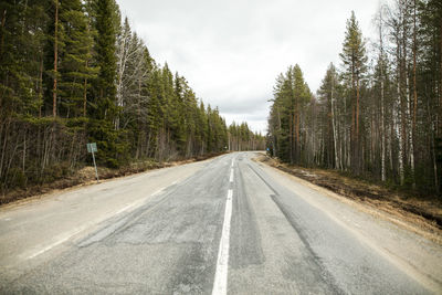 Road amidst trees in forest against sky