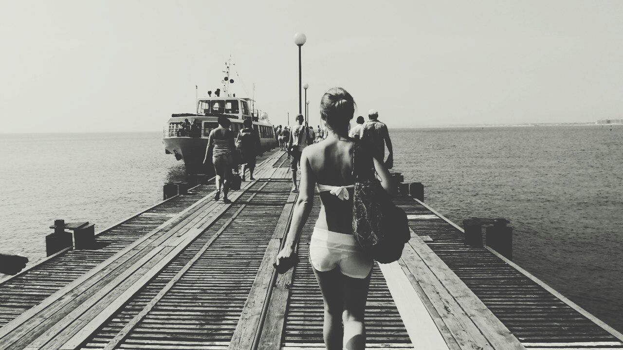 sea, water, lifestyles, rear view, railing, leisure activity, full length, horizon over water, pier, men, clear sky, person, standing, sky, casual clothing, looking at view, togetherness