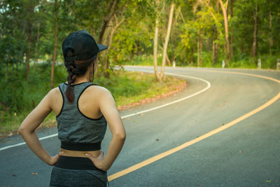 Rear view of athlete exercising on road amidst trees