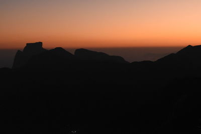 Scenic view of silhouette mountains against orange sky