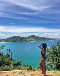 Woman standing on mountain over sea against sky