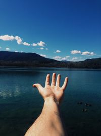 Midsection of person on lake against sky
