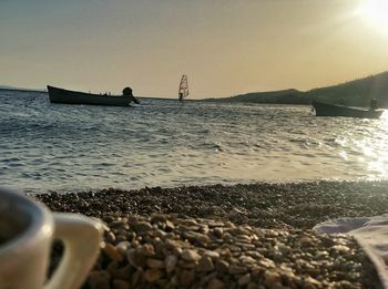 Cropped image of boat sailing in sea at sunset
