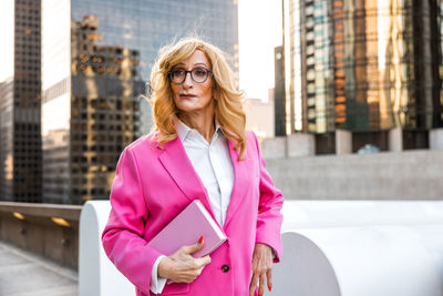 Portrait of young woman standing against building