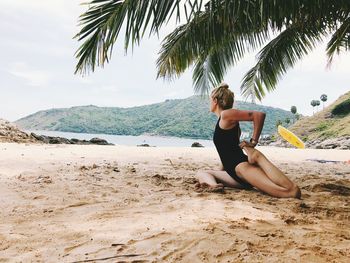 Side view of woman practicing yoga at beach