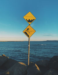 Information sign by sea against blue sky