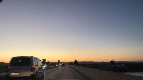 Cars on road against sky during sunset