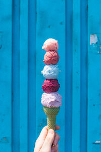 Human hand holding ice cream nicely colored ice cream cone on a sunny day