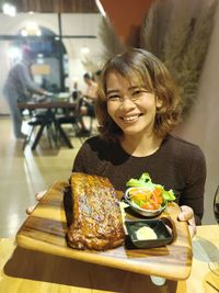 Portrait of smiling young woman sitting on table