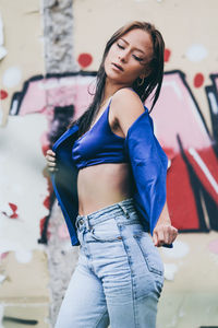 Beautiful young woman standing against wall