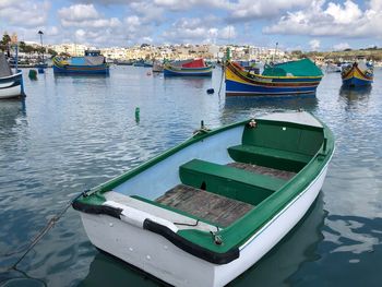 Boats moored at harbor against sky