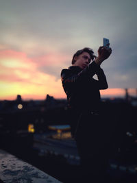 Full length of young woman photographing at sunset