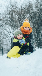 Rear view of a girl and boy playing in snow