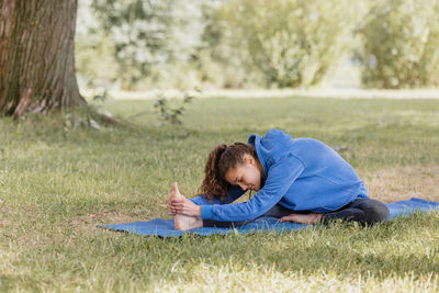 Young woman using laptop while sitting on field