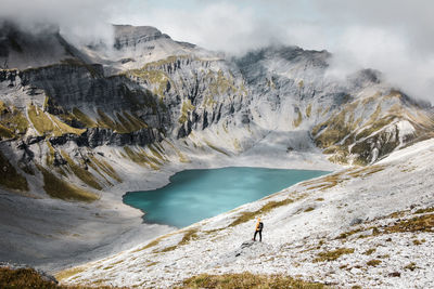 High angle view of male hiker standing on snow covered mountain