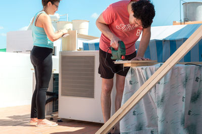 Couple working together to build furniture on the rooftop of a house.