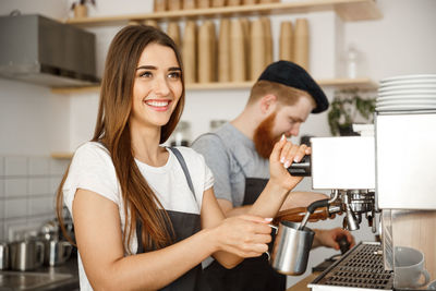 Smiling young woman having food in kitchen