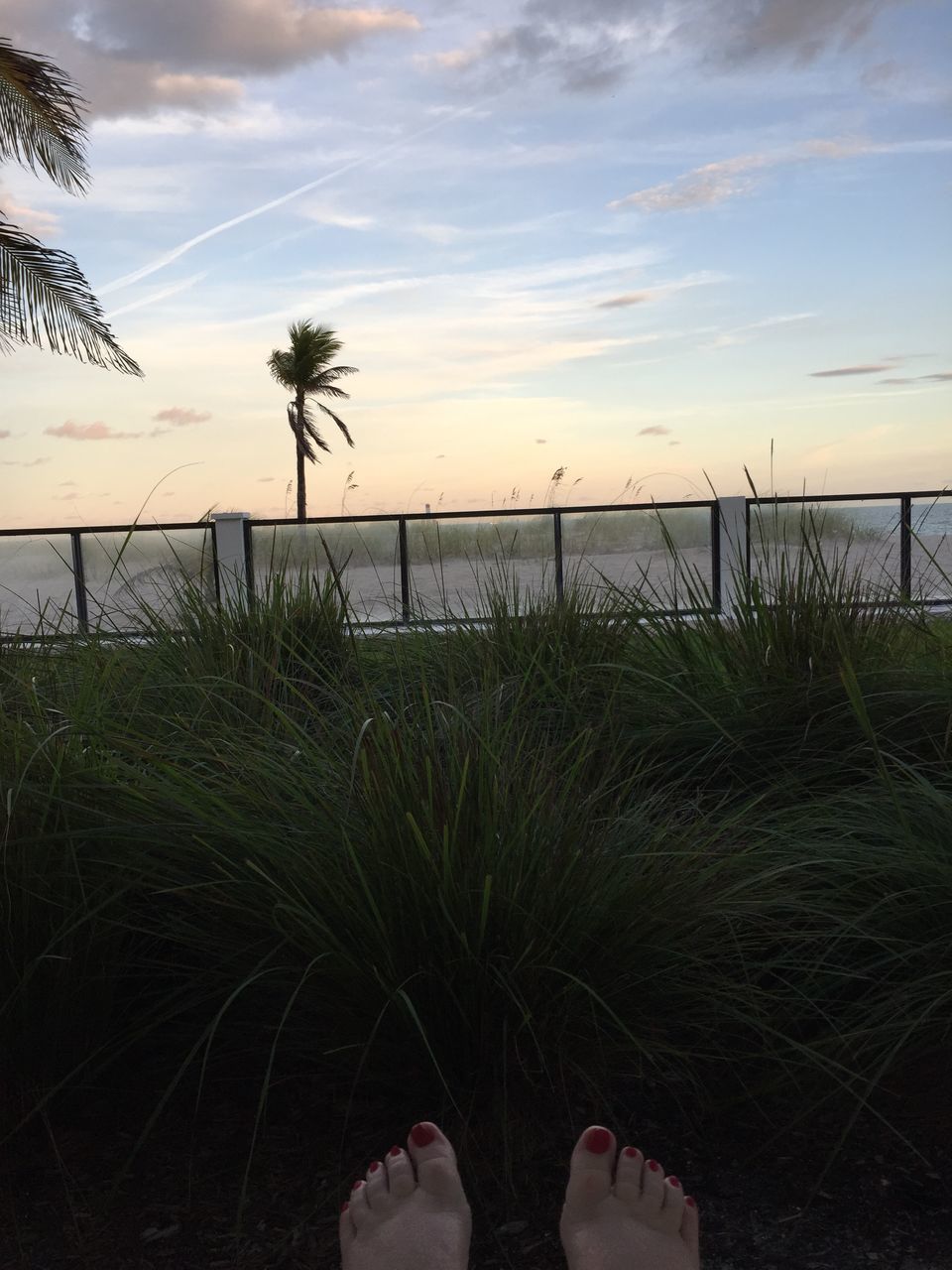 LOW SECTION OF PERSON ON BEACH AGAINST SKY