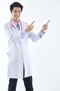 Full length of a smiling young woman standing against white background